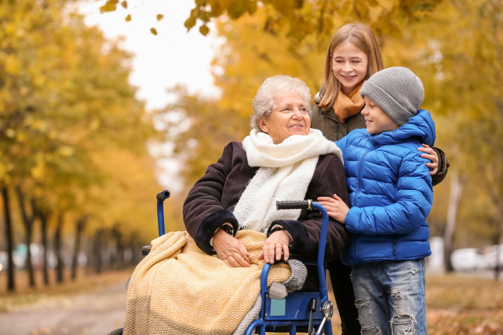 elder woman in a wheelchair with two children, smiling