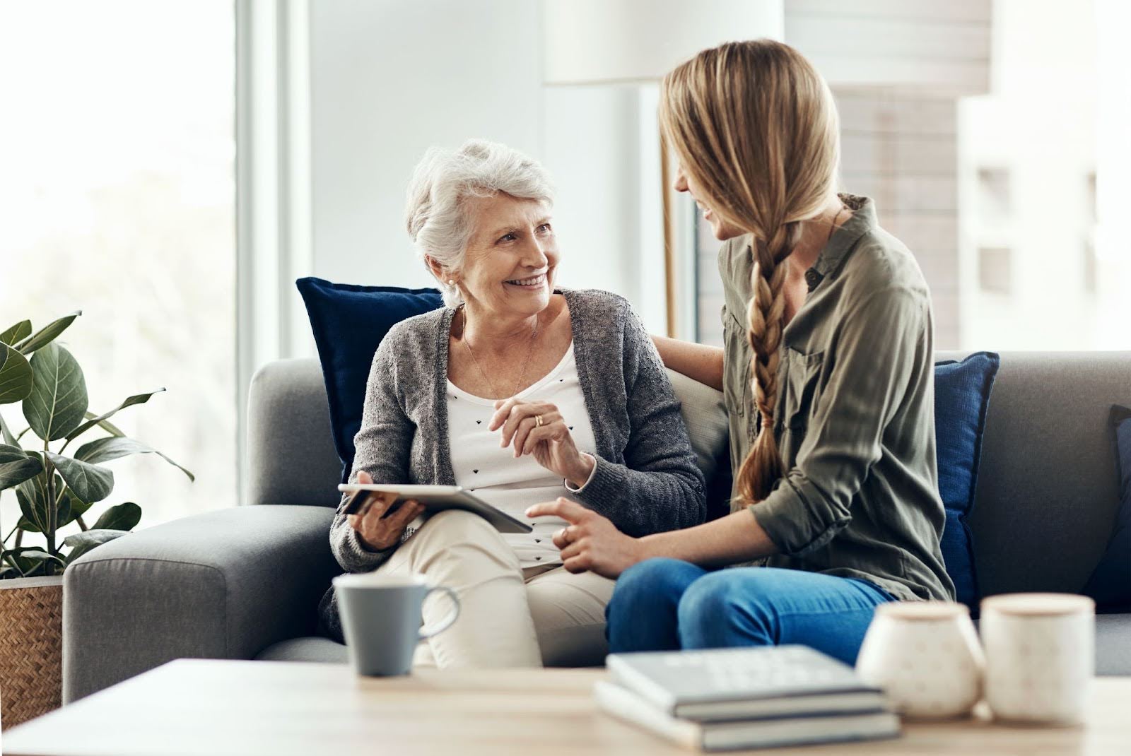 older woman and younger woman sitting on a couch, smiling