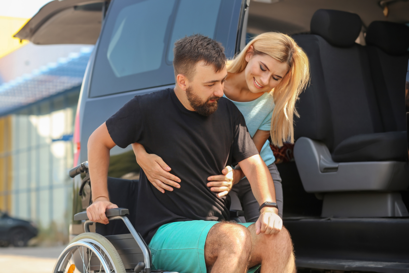 young woman lifting young man in wheelchair