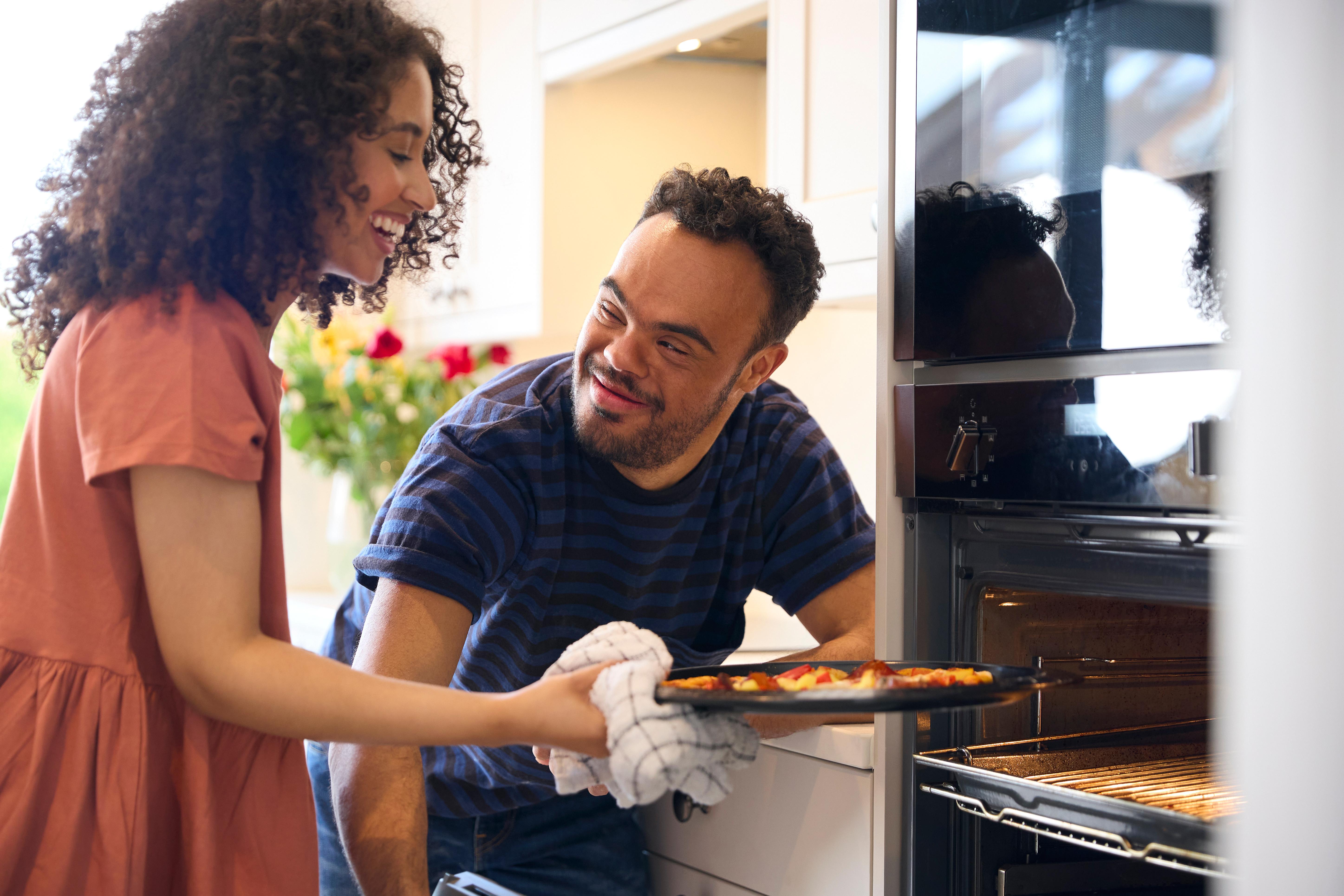 Woman helps man remove item from oven