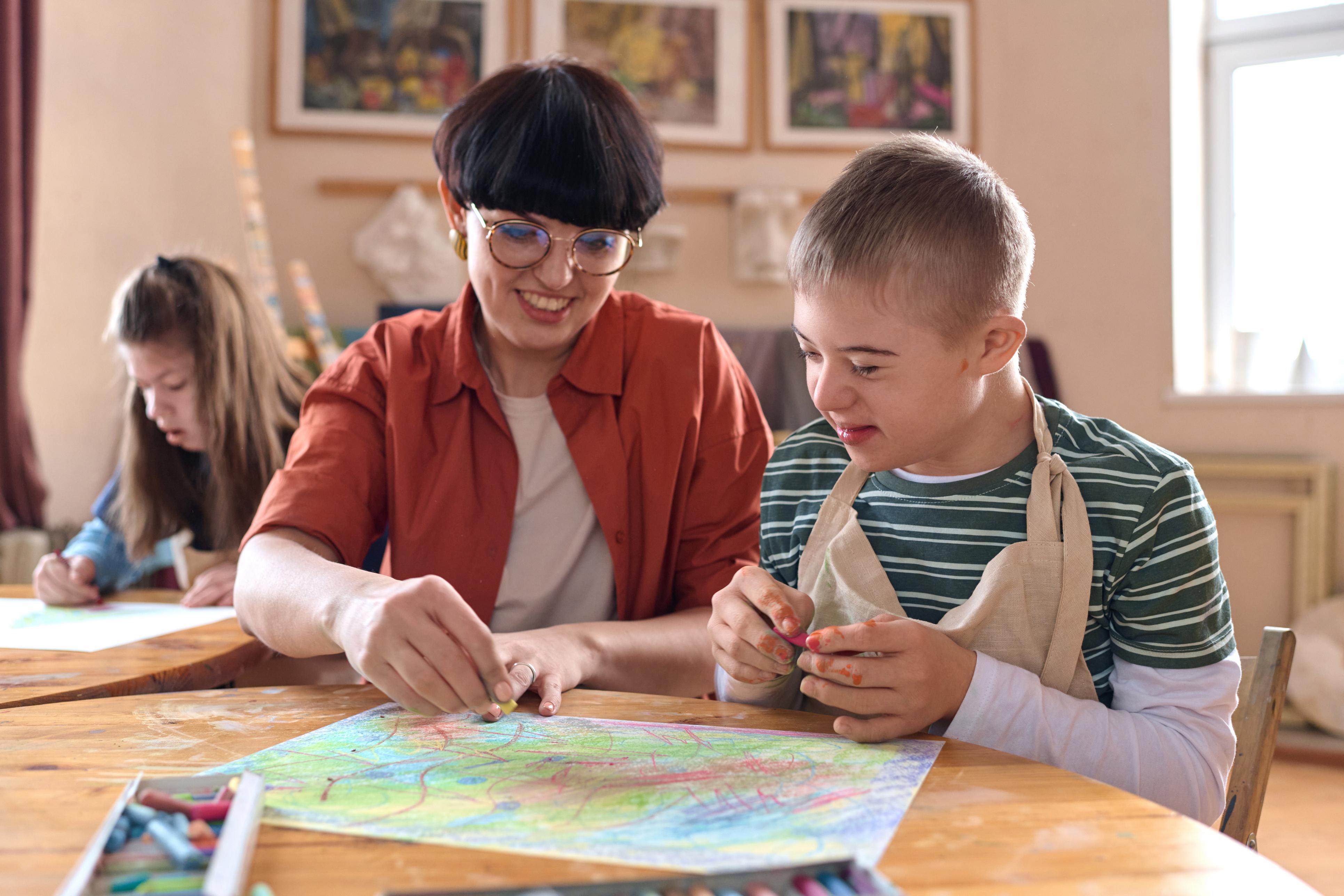 caregiver and boy with down syndrome doing school work
