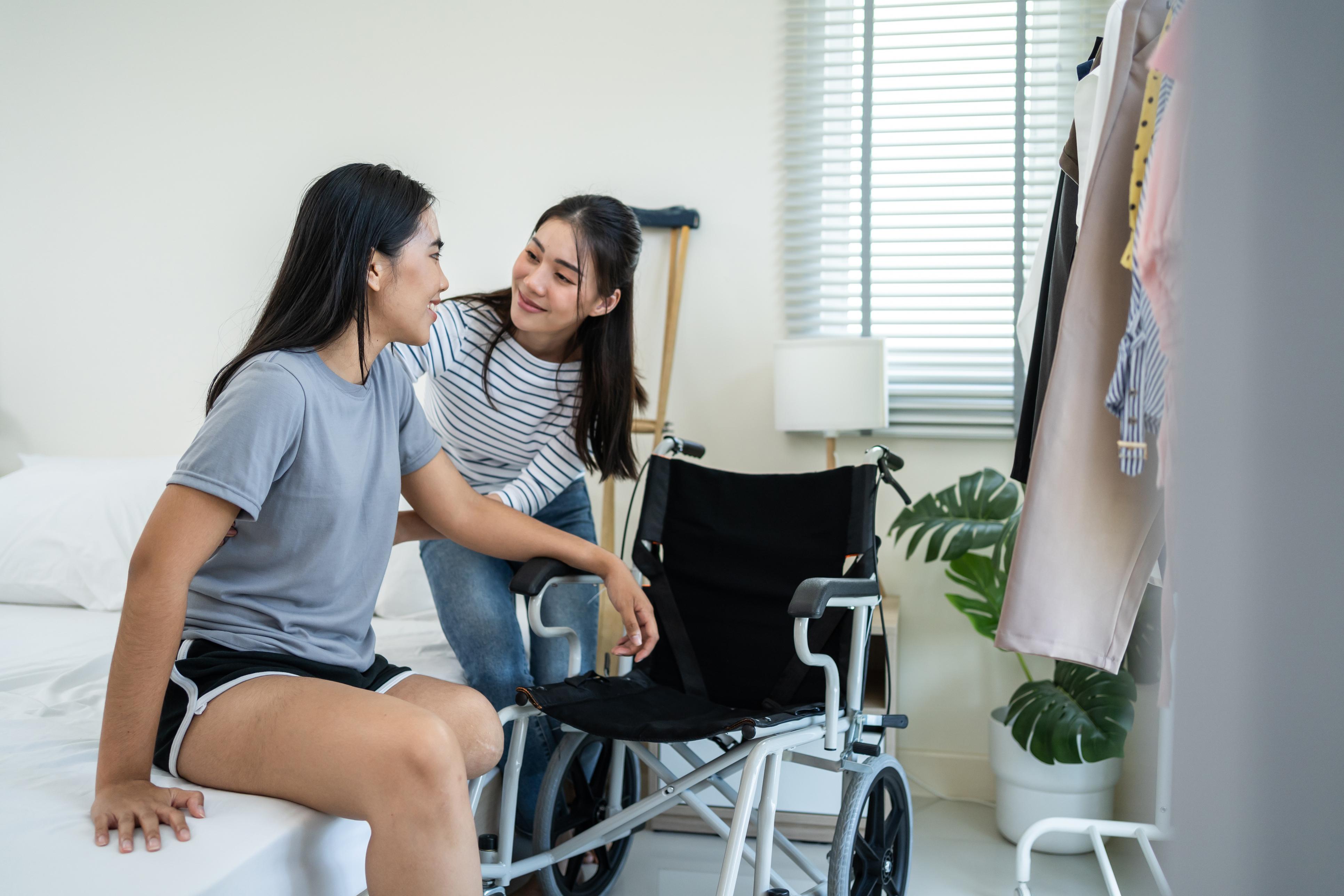 caregiver helping wheelchair user out of bed
