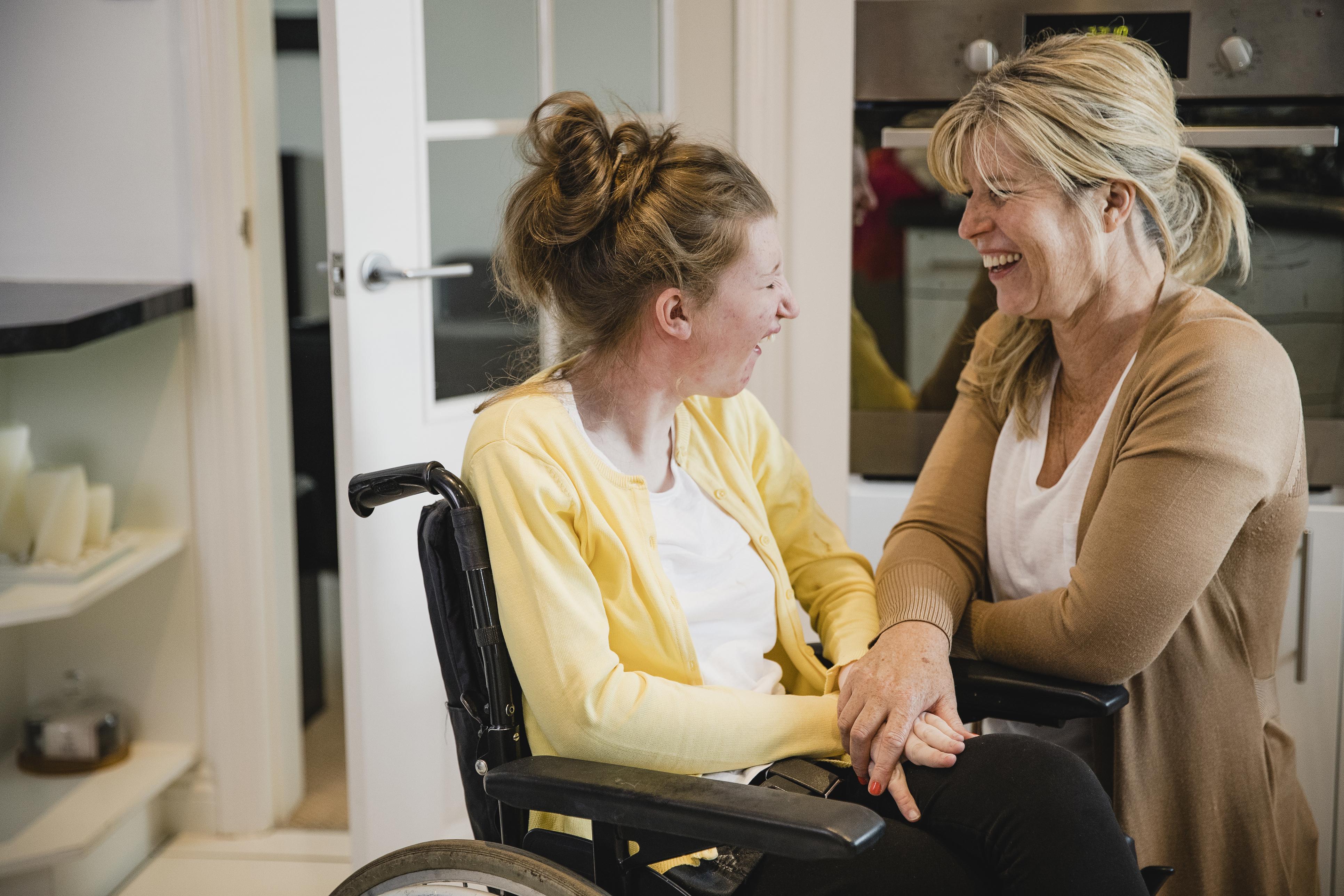 Female in wheelchair with female caregiver laughing