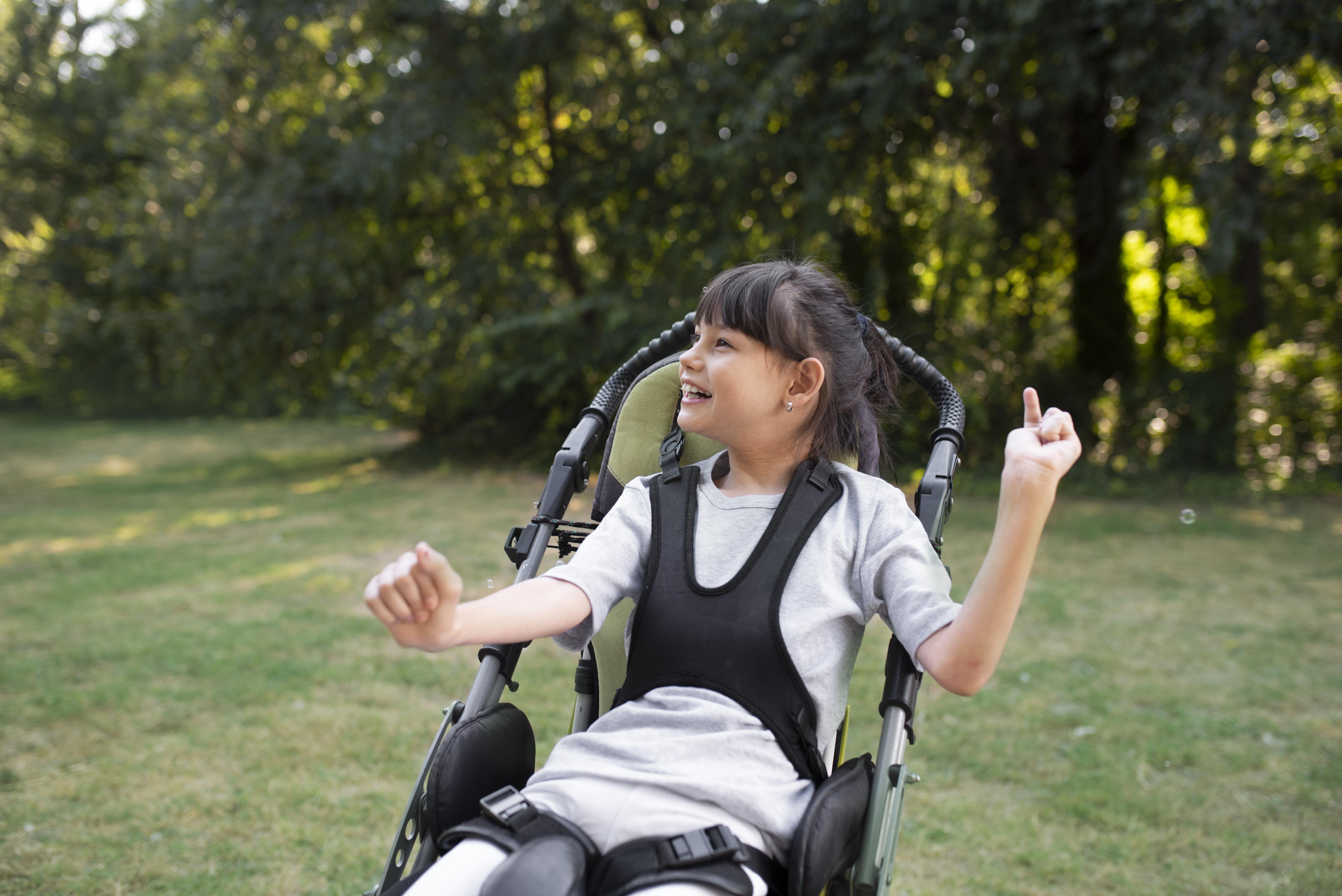 Young girl using wheelchair smiling in the park