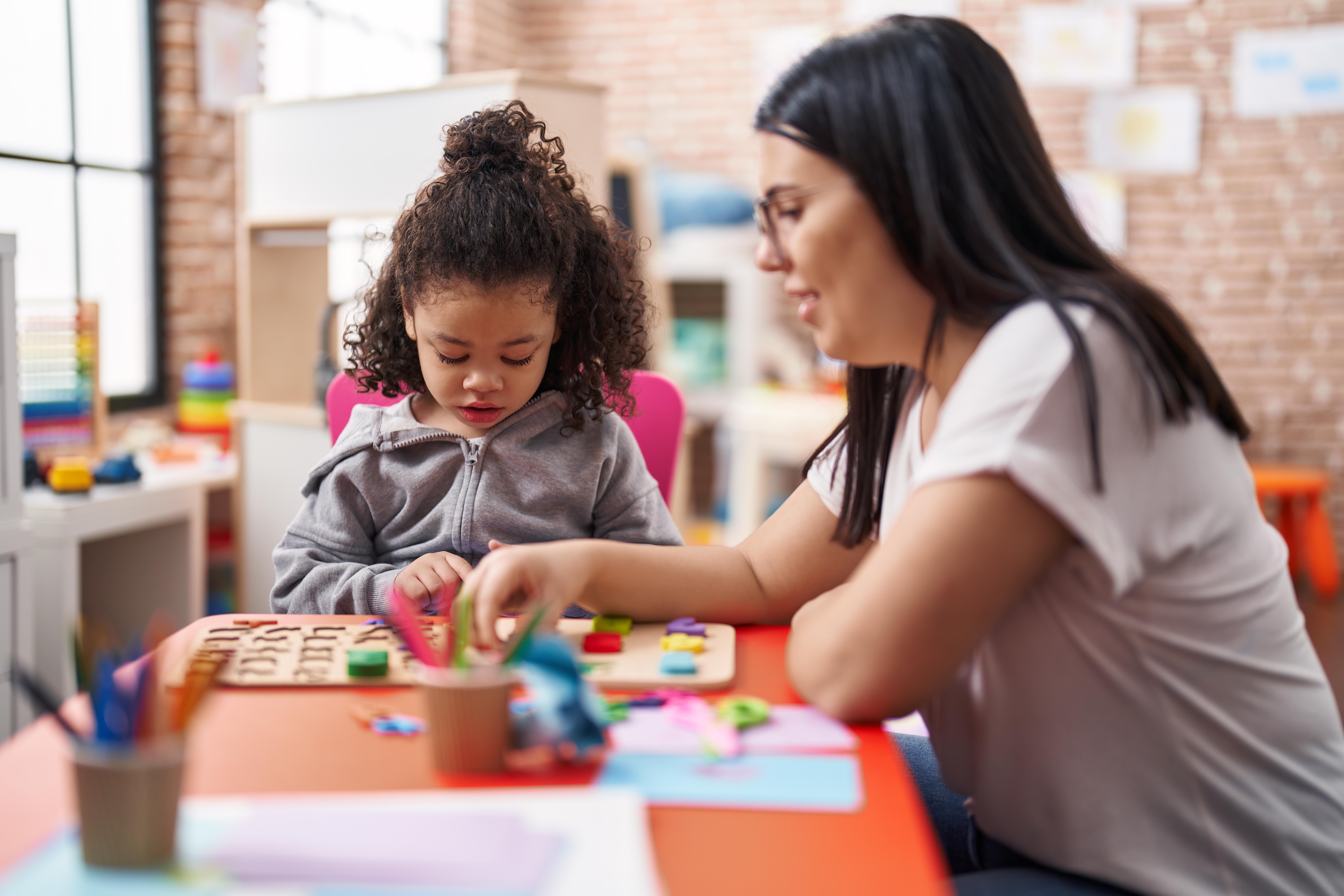 female caregiver and young girl doing a puzzle