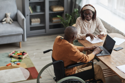 Man using a wheelchair and a woman sitting at a table talking.
