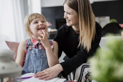 Caregiver and young girl smiling together